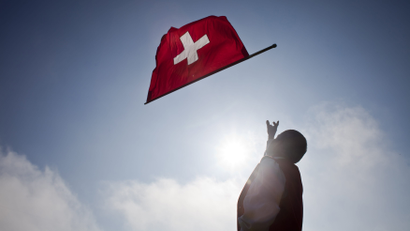 A man throws a Swiss national flag