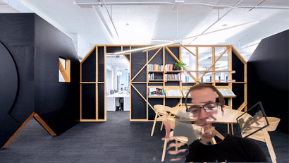 The author appears in front of a Zoom background of the Quartz office. Much of his face and body have been blurred into the background.