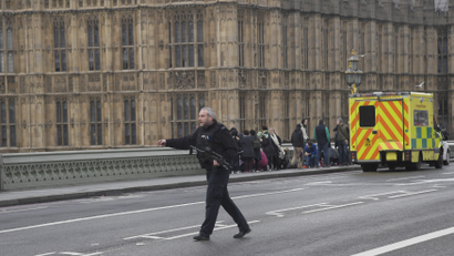 An armed police officer runs accross the road during an incident on Westminster Bridge in London