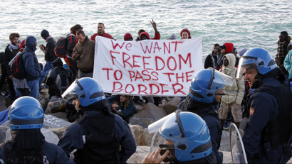 Migrants and activists hold a banner as they face off with Italian police on the seawall at the Saint Ludovic border crossing on the Mediterranean Sea between Ventimiglia, Italy and Menton, France, September 30, 2015.