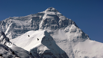 Two birds fly in front of the summit of the world's highest mountain Mount Everest, also known as Qomolangma, in the Tibet Autonomous Region
