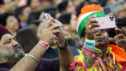 People take photos with their mobile phones as they participate in the "Howdy Modi" event in Houston