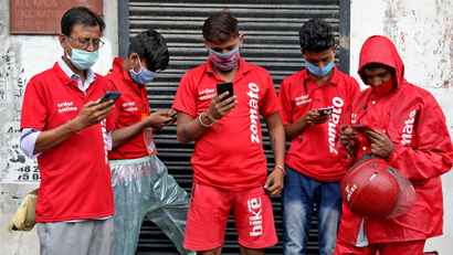 FILE PHOTO: Delivery workers of Zomato wait to collect orders outside a restaurant in Kolkata