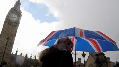 A woman carries a British union flag design umbrella as she walks past the Houses of Parliament in London, Britain