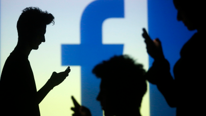 People are silhouetted as they pose with mobile devices in front of a screen projected with a Facebook logo, in this picture illustration taken in Zenica October 29, 2014. Facebook Inc warned on Tuesday of a dramatic increase in spending in 2015 and projected a slowdown in revenue growth this quarter, slicing a tenth off its market value. Facebook shares fell 7.7 percent in premarket trading the day after the social network announced an increase in spending in 2015 and projected a slowdown in revenue growth this quarter. REUTERS/Dado Ruvic (BOSNIA AND HERZEGOVINA - Tags: BUSINESS SCIENCE TECHNOLOGY BUSINESS LOGO) - RTR4C0VB