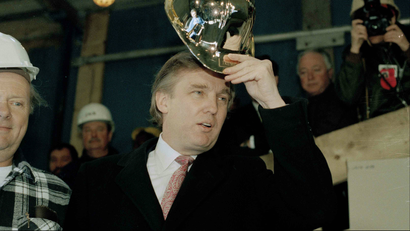 Donald trump tries on a gold hard hat presented to him by construction workers at Trump Palace in New York
