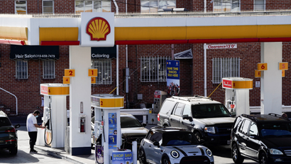 People refuel their vehicles with gasoline at a Shell gas station.