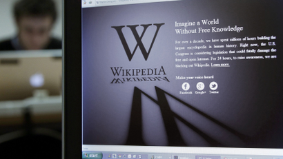 A laptop screen displays the Wikipedia homepage.