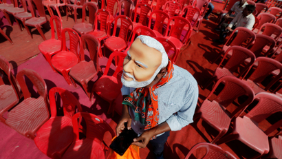 A supporter of India's ruling Bharatiya Janata Party (BJP) wearing a mask of Prime Minister Narendra Modi checks his mobile phone as he attends an election campaign rally being addressed by Modi in Meerut