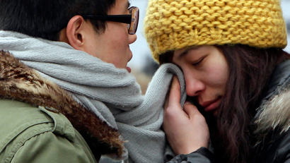 A woman wipes her tears with her partner's scarf as they part in Beijing