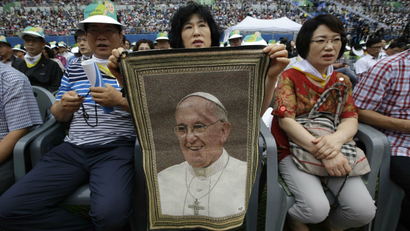 A woman in South Korea holds up a Pope Francis rug as she waits for him to address the crowd.