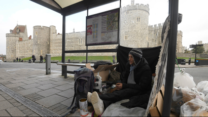 A homeless man sits under a bus shelter where he sleeps opposite Windsor Castle