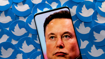 Elon Musk's face on a phone with Twitter logos