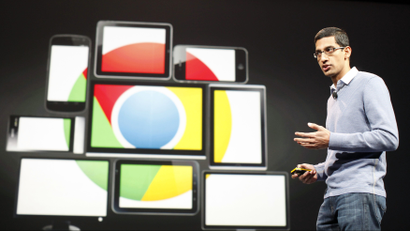 Sundar Pichai stands in front of a group of screens displaying the Google Chrome logo.