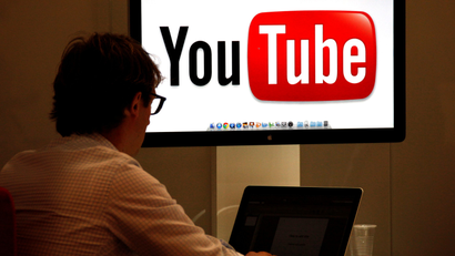 A person working in front of a screen with YouTube's logo.