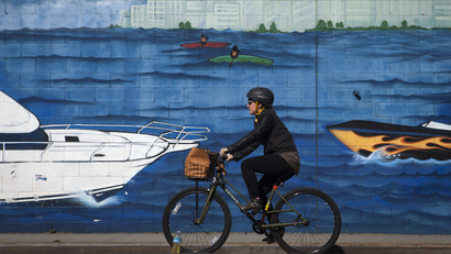 A cyclist rides past a mural on the side of a storage facility building in Brooklyn