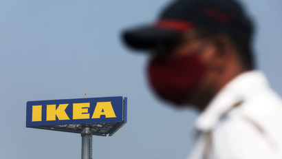 A man in a mask stands in front of an IKEA sign