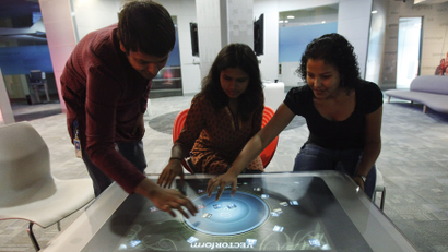 Employees demonstrate the use of the newly-designed prototype of a touch-sensitive table at Microsoft India's Development Center in the Gachibowli IT district in Hyderabad