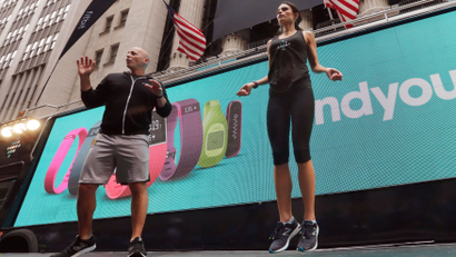 Fitness expert Harley Pasternak, left, and actress Jordana Brewster lead a work out, on behalf of Fitbit, in front of the New York Stock Exchange, Thursday, June 18, 2015. Fitbit flexed some muscle Thursday and its shares rocketed 50 percent higher in the first day of trading for the fitness tracking gear maker. (AP Photo/Richard Drew)