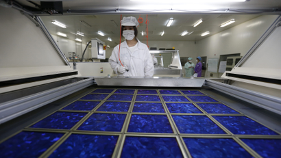 An employee dries newly made solar panels at a factory of a photovoltaic company in Jiaxing, Zhejiang province June 5, 2013.