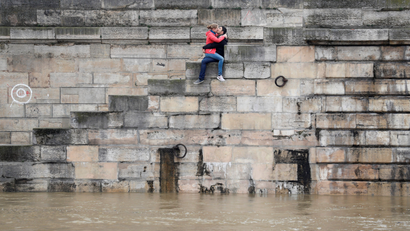A couple exchanges kisses on the bank as high waters causes flooding along the Seine River in Paris