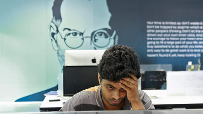 An employee works on a computer terminal against the backdrop of a picture of late Apple co-founder Jobs at the Start-up Village in Kinfra High Tech Park in Kochi