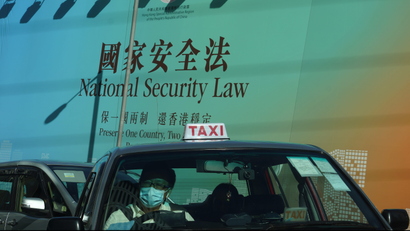 A taxi drives past a big banner featuring the Hong Kong National Security Law in Hong Kong, Monday, June 29, 2020.