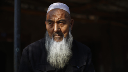 An ethnic Uighur man sits outside his house near a busy market in Turpan, Xinjiang province October 31, 2013
