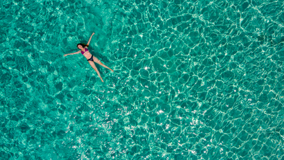An aerial view shows a woman floating peacefully in the sea