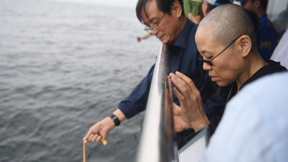 In this photo provided by the Shenyang Municipal Information Office, Liu Xia, the wife of imprisoned Chinese Nobel Peace Prize laureate Liu Xiaobo, watches as Liu's ashes are buried at sea off the coast of Dalian in northeastern China's Liaoning Province, Saturday, July 15, 2017. China cremated the body of Liu on Saturday, July 15, 2017, who died this week after a battle with liver cancer amid international criticism of Beijing for not letting him travel abroad as he had wished.
