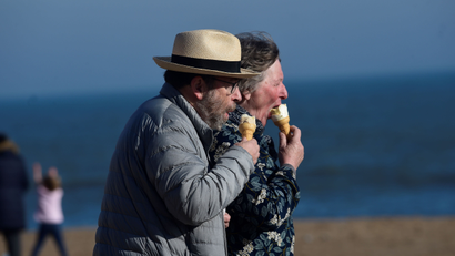 A couple eat ice-creams in the sunshine at South Beach, Tenby, Pembrokeshire, Wales, Britain