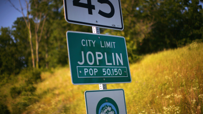 A photograph of a road sign reading "city limit Joplin, pop 50,150"