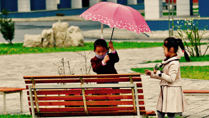 Girl opens umbrella at bench.