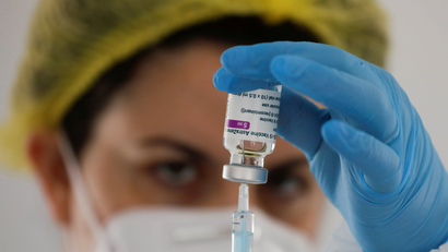 A person uses a syringe to take out AstraZeneca's vaccine from a vial