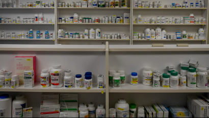 Bottles of medications line the multiple shelves at a pharmacy.