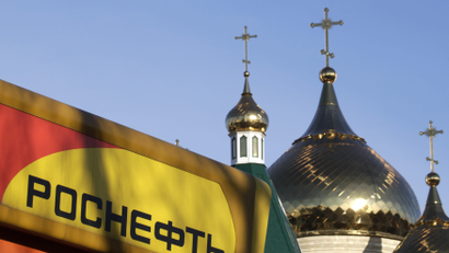 The logo of Russia's top crude producer Rosneft is seen on a gasoline station near a church in Stavropol