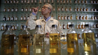 In this March 8, 2017 photo, Suntory's chief blender Shinji Fukuyo demonstrates how he examines the whisky at the Suntory distillery in Yamazaki, near Kyoto, western Japan. "What’s important for whisky is that its deliciousness must deepen with aging, sitting in the casks for a long time," said Fukuyo, 55, demonstrating how he examines the whisky in a glass, swirling the crystalline amber spirit against the light.
