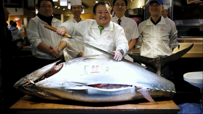 Kiyomura Co's President Kiyoshi Kimura (C), who runs a chain of sushi restaurants, holds a sword as he poses with a 200 kg (400 lbs) bluefin tuna at his sushi restaurant outside Tsukiji fish market in Tokyo, Japan, January 5, 2016. Kimura won the bid for the tuna caught off Oma, Aomori prefecture, northern Japan, with a 14 million yen (117,000 USD) at the fish market's first tuna auction this year. REUTERS/Toru Hanai