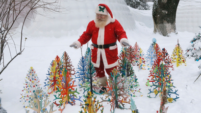 A man dressed as Santa Claus walks in deep snow looking at small artificial Christmas trees in a snowy city park in Kiev, Ukraine, Tuesday, Jan. 10 2017. The temperature in Kiev is -6 degrees Centigrade (22 degrees Fahrenheit). (AP Photos/Efrem Lukatsky)