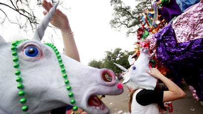 Women, wearing unicorn masks, scream for beads as members of the Krewe of Mid-City parade down St. Charles Avenue during the weekend before Mardi Gras in New Orleans