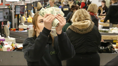 Cashier Nikki Hall checks the cash given to her at the register in the check out line at a crowded Crest Fresh Market grocery store in Edmond, Oklahoma.