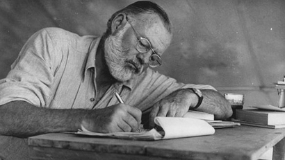 Ernest Hemingway writing at a desk