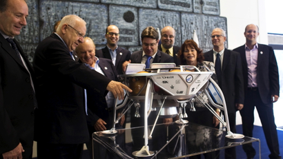 Israeli President Reuven Rivlin (2nd L), Minister of Science, Technology and Space, Ofir Akunis (5th L) and members of the Israeli team, SpaceIL, look at a model of an Israeli spacecraft, during a meeting in Jerusalem October 7, 2015. The Israeli team competing in a race to the moon sponsored by Google has signed a with California-based SpaceX for a rocket launch, putting it at the front of the pack and on target for blast-off in late 2017, officials said on Wednesday.