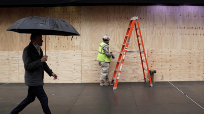 Workers use sheets of plywood to cover the windows of Macy's department store