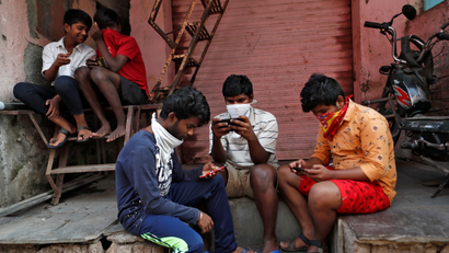 A group of boys in Mumbai look at their smartphones.