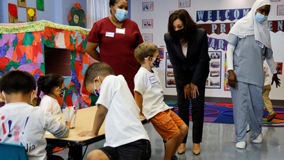 Vice President Kamala Harris wears a face mask while talking with children and a teacher in a classroom
