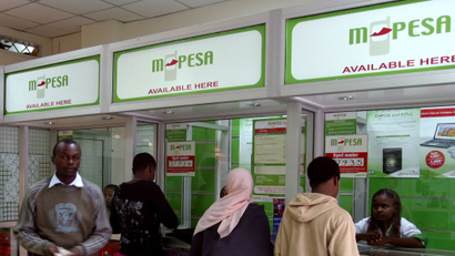 A man leaves an M-PESA booth after a money transaction in Nairobi May 12, 2009. Teaming up with Kenya Commercial Bank to let phone users who do not have bank accounts send each other money, M-PESA, the virtual cash network, hit on a formula that has attracted 6.5 million customers, or one in six Kenyans, in just over two years. Picture taken May 12, 2009.