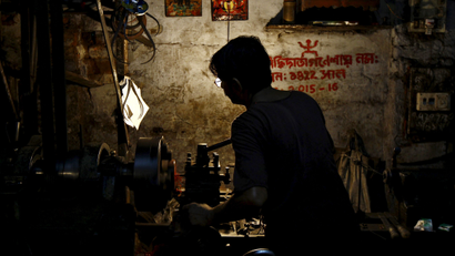 A worker operates a lathe machine as he makes car parts inside a small scale manufacturing unit in Kolkata