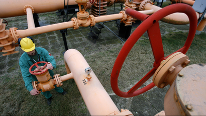 A worker controls a gas valve at a pipeline.