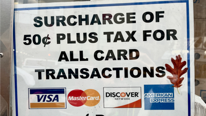 A sign that reads "surcharge of 50 cents plus tax for all card transactions".
